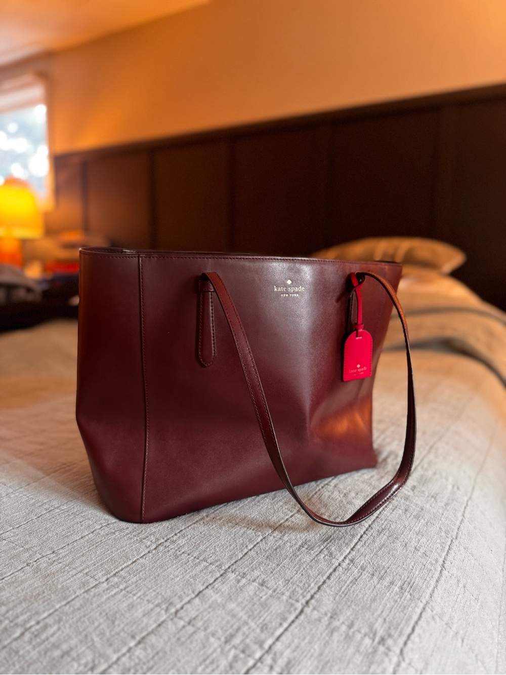 kate spade burgundy leather tote with pink luggage tag
